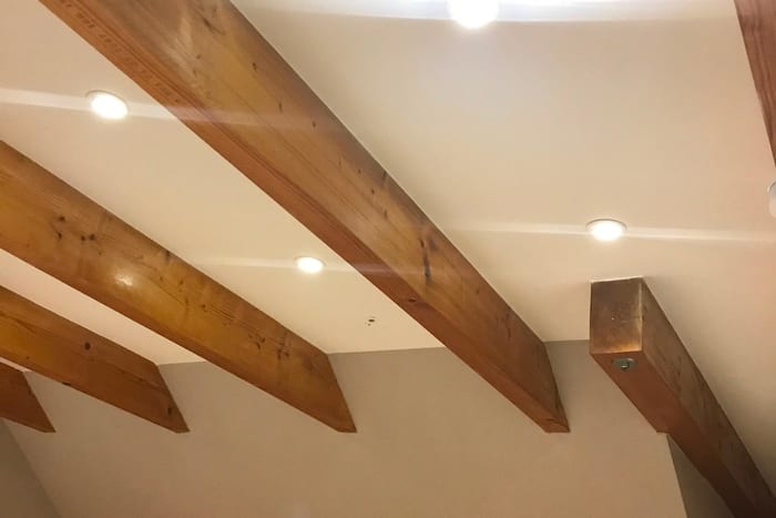 Ausgebautes Dachgeschoss mit sichtbaren Holzbalken und bündig eingelassenen Deckenspots