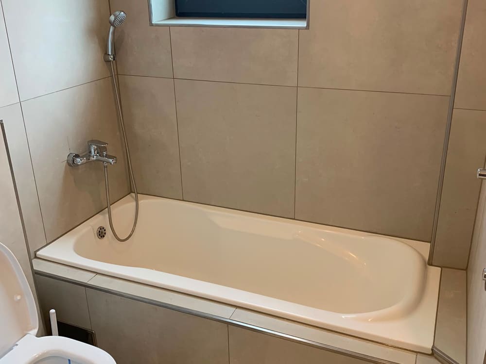 Dasselbe Badezimmer fertiggestellt: gefliest, mit Wanne, Armatur und WC